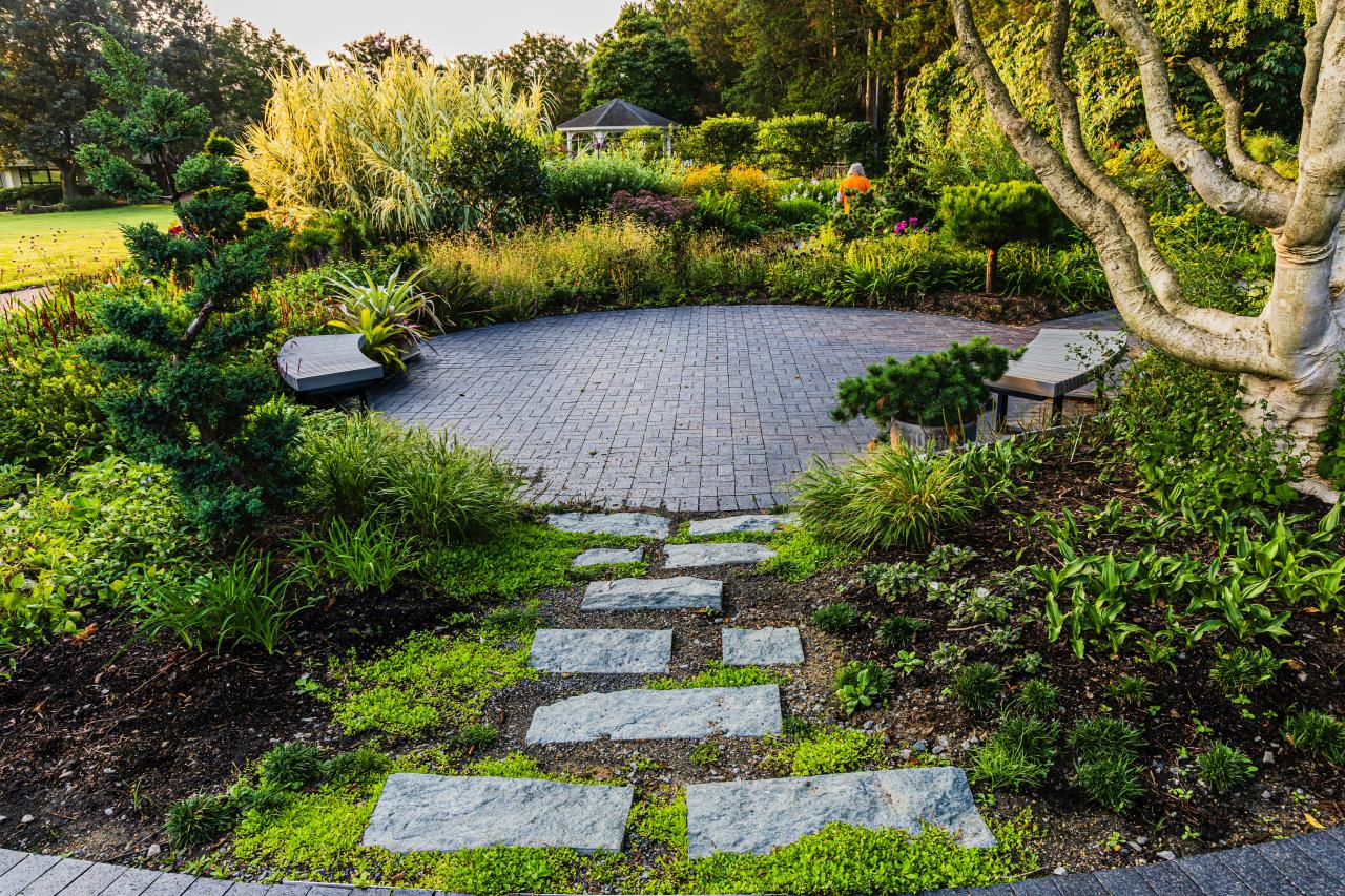 Stone path leading to a circular patio within a planted garden