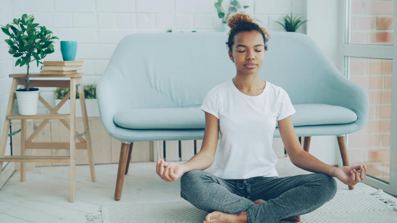 Person meditating on a clear floor area in a home wellness space